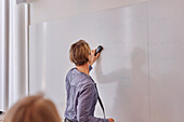 Woman writing on whiteboard during meeting
