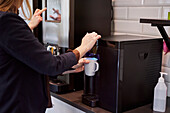 Frau bereitet Kaffee in der Büroküche zu