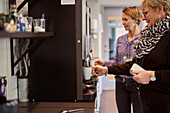 Frau bereitet Kaffee in der Büroküche zu