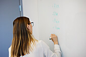 Frau schreibt während eines Meetings auf ein Whiteboard