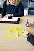 Menschen, die während eines Meetings auf Post Its schreiben