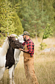 Landwirt streichelt Pferde auf einem Feld