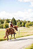 Landwirt reitet Pferd auf der Landstraße