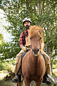 Bauer mit Helm reitet Pferd