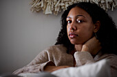 Portrait of pensive young woman sitting at home