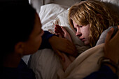 Junge Frau tröstet Freund im Bett liegend