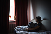 Pensive man sitting on sofa and looking through window