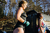 Frau bereitet sich auf das Schwimmen vor, im Hintergrund die Sauna