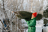 Lächelnde Frau trägt Weihnachtsbaum