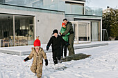 Glückliche Familie im Winter vor dem Haus