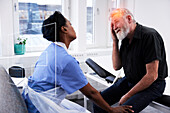 Älterer Mann mit Kopfschmerzen bei einem Arzttermin