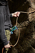 Mid section of rock climbers hands holding rope