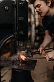 Male blacksmith forging metal in workshop