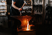 Männlicher Schmied beim Hämmern von Metall in der Werkstatt
