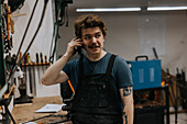 Male blacksmith talking on phone in workshop