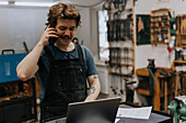 Blacksmith talking on phone in workshop