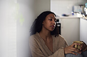 Pensive young woman sitting at home