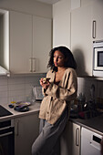 Pensive young woman standing in kitchen