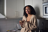 Portrait of smiling young woman standing in kitchen