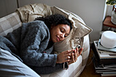 Young woman lying on sofa and using phone