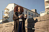 Schöne Frau mit Takeaway-Kaffee und Smartphone auf der Straße