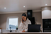 Woman in kitchen talking via cell phone