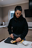 Woman cutting banana in kitchen