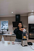 Woman using blender in kitchen