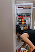 Frau steht vor einem offenen Kühlschrank