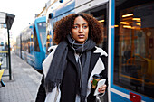 Young woman walking, tram in background