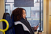 Young woman using cell phone in bus