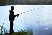 Side view of woman fishing at lake