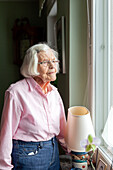 Ältere Frau blickt durch das Fenster