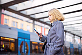 Woman using cell phone at tram stop