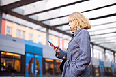 Frau mit Handy an der Straßenbahnhaltestelle