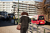 Rückansicht einer Frau, die auf eine Bushaltestelle zugeht
