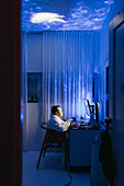 Junge am Schreibtisch mit Computer in der Nacht