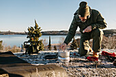 Mann bereitet im Winter Essen im Freien zu