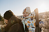 Smiling toddler in baby carrier looking at camera