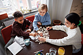 Mädchen und Jungen spielen Scrabble am Esstisch