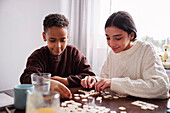 Girl and boy playing scrabble at dining table