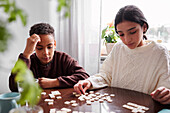 Mädchen und Junge spielen Scrabble am Esstisch