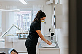 Female dentist washing hands in office