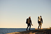 View of backpackers walking at sea