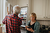 Älteres Ehepaar öffnet den Kühlschrank und telefoniert zu Hause