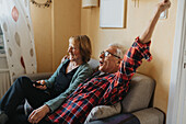 Senior couple sitting on sofa and singing