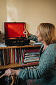 Senior woman using gramophone at home