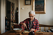 Älterer Mann bei der Essenszubereitung zu Hause