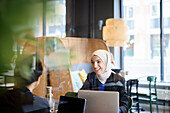 Frau mit Kopftuch im Café sitzend