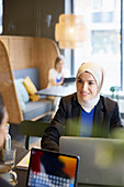 Frau mit Kopftuch im Cafe sitzend